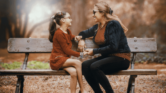 Mother and daughter talking on bench