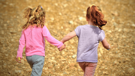 Two girls running holding hands