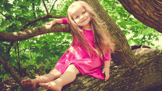 Girl in pink dress climbing tree