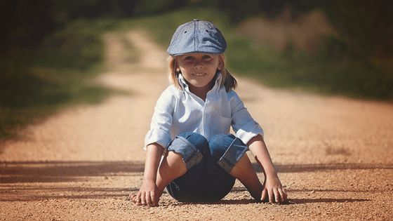 Happy Child Sitting On Road