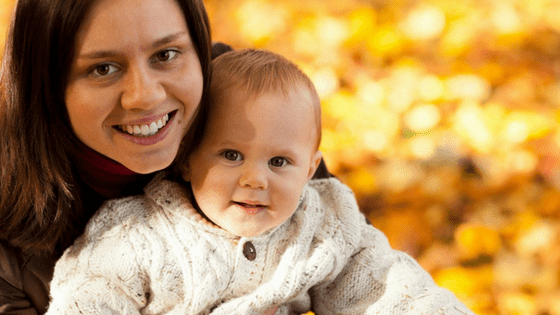 Woman holding baby autumn leaves background