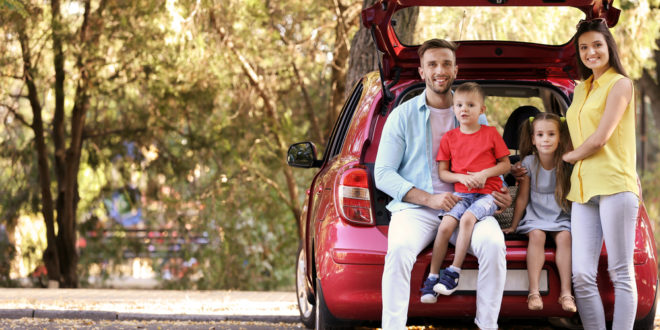 Family standing by red car