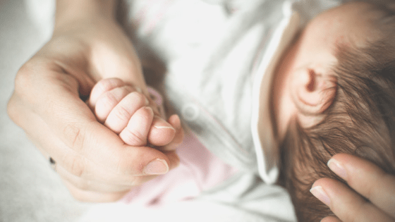 Cuddling Newborn Baby Holding Hand