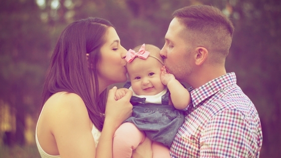 Parents kissing baby girl