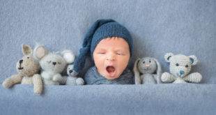Newborn boy in bed with toys