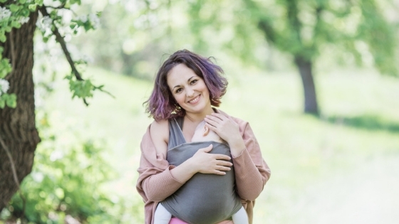 Happy woman holding baby in wrap