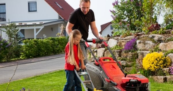 Man mowing lawn with daughter