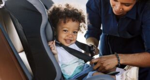 Mom buckling toddler into car seat